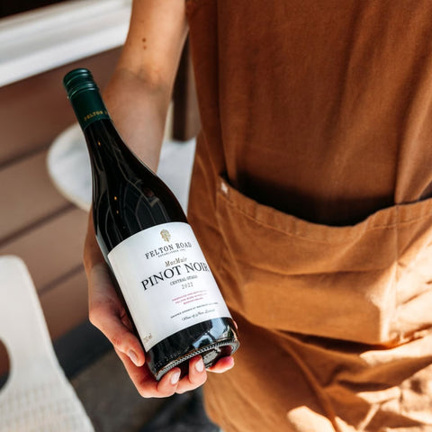 Woman holding a bottle of Felton Road Pinot Noir Wine wearing a brown smock